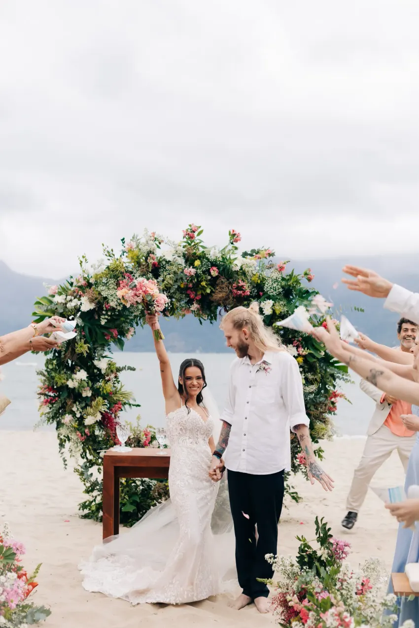 Convidados acompanhando a cerimônia, corredor decorado com flores na areia