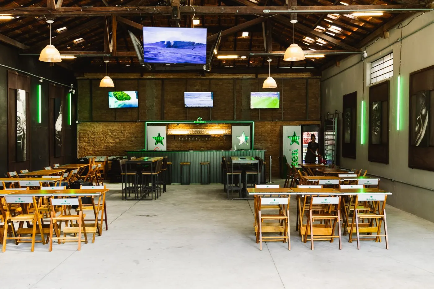 Salão interno do Farofa com mesas, bar e TVs