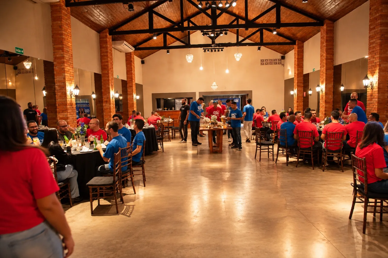 Evento corporativo no salão da Villa Pacaembu, com equipes reunidas entre mesas e pé-direito alto