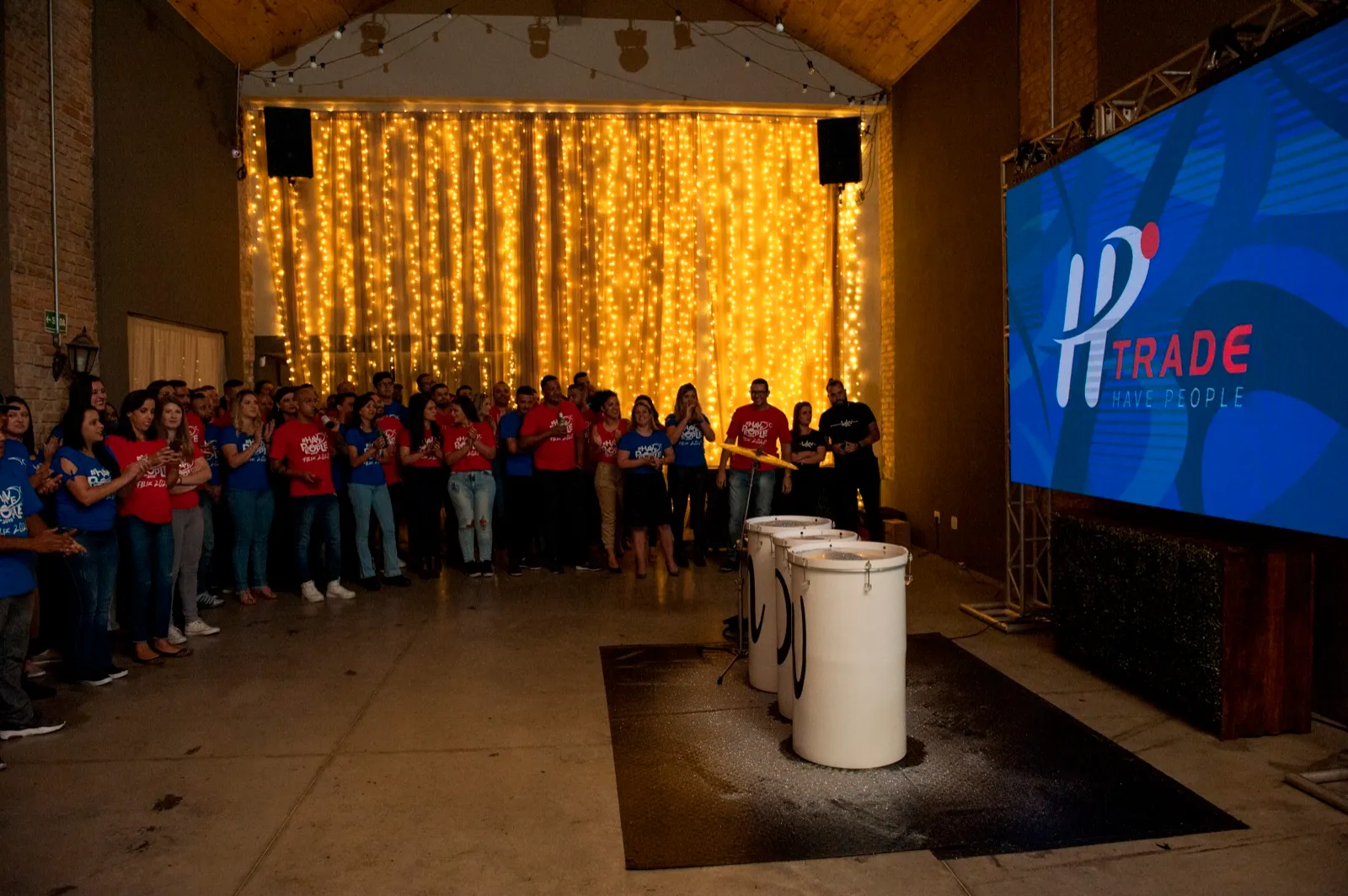 Equipes reunidas diante do telão e da cortina de luzes
