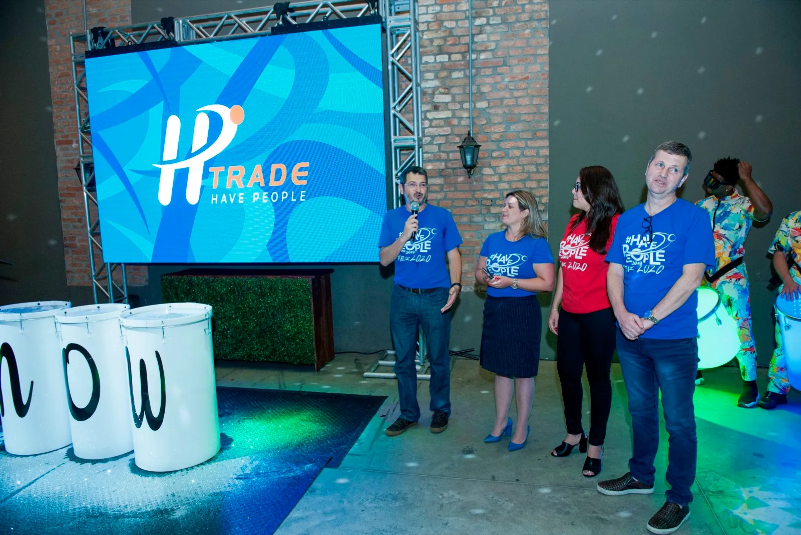 Equipe no palco em frente ao telão de LED durante evento corporativo