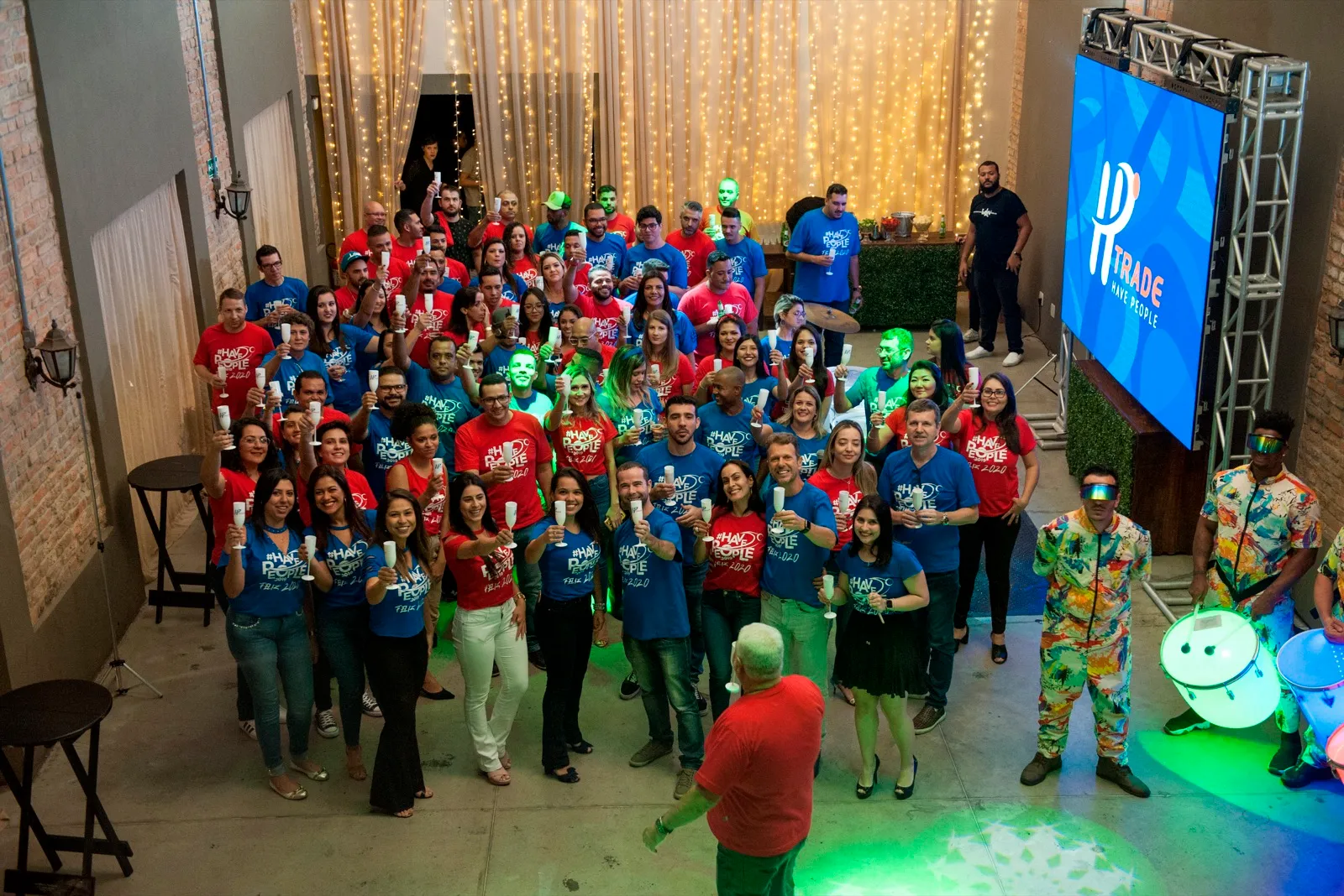 Grande grupo de colaboradores reunidos diante do telão
