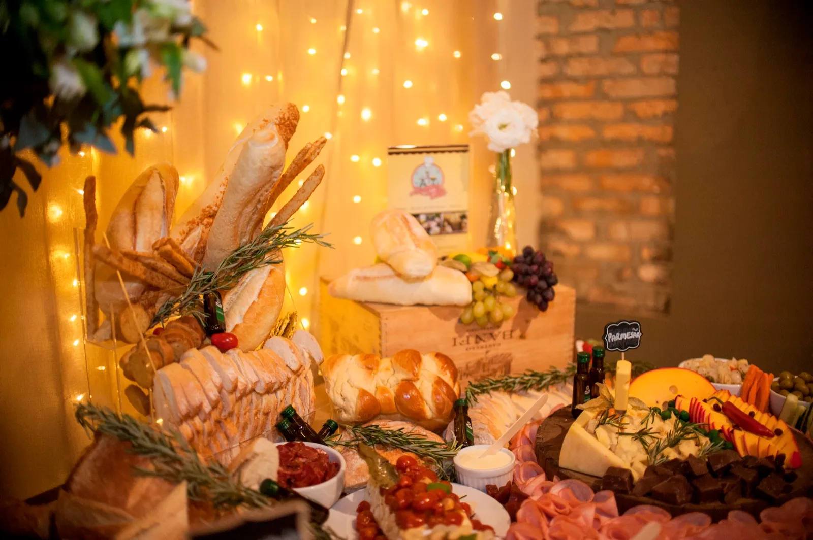Mesa de pães, queijos e frios decorada com ramos e luzes