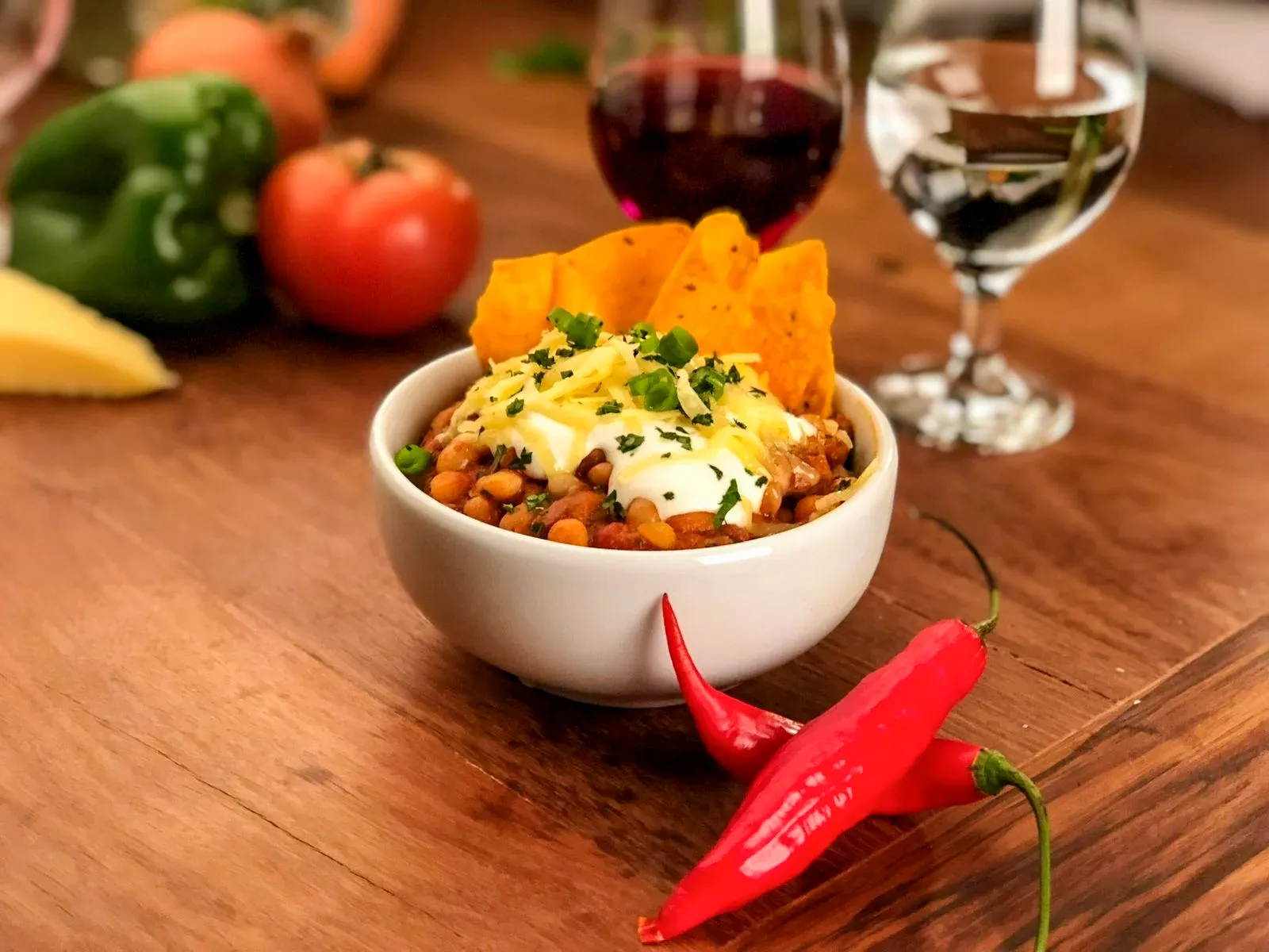 Porção de chili com nachos servida com taças de vinho